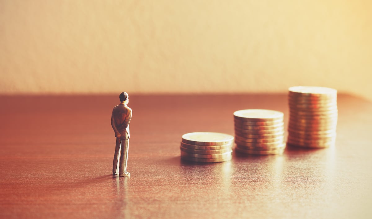 Minature man looking at coins to signify recession